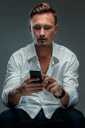 Portrait of handsome man in white shirt with mobile phone.の写真素材