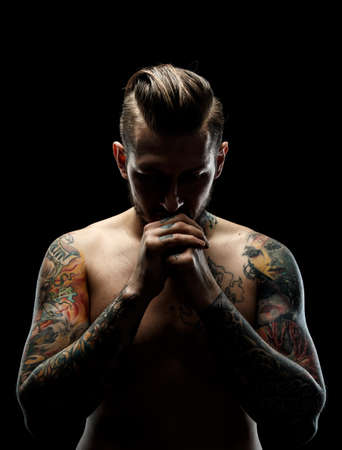 Portrait of a man with naked torso and tattooes. Dark and deep shadows.の写真素材