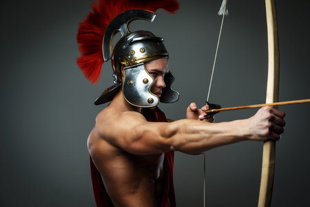 Wounded gladiator with bow isolated on grey.