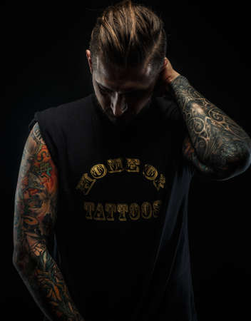 Portrait of a man in black t shirt and tattoos. Dark and deep shadows.の写真素材
