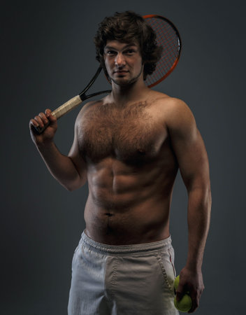 Male tennis player poses in studio. Isolated on grey.の写真素材