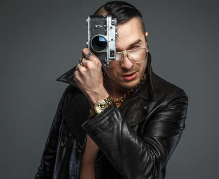 Male in skin coat holds photo camera.の写真素材
