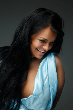 Portrait of dark haired woman in blue dress isolated on greyの写真素材