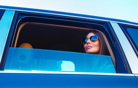 Young happy awesome woman in sunglasses looking from a carの写真素材