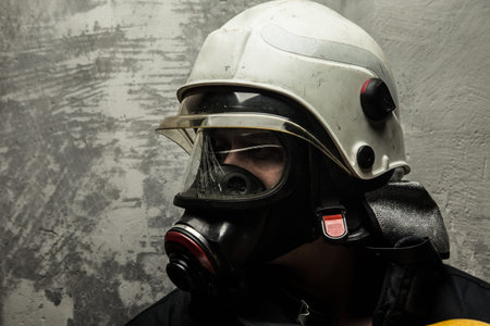 Male in oxygen mask and firefighter helmet on grey backgroundの写真素材