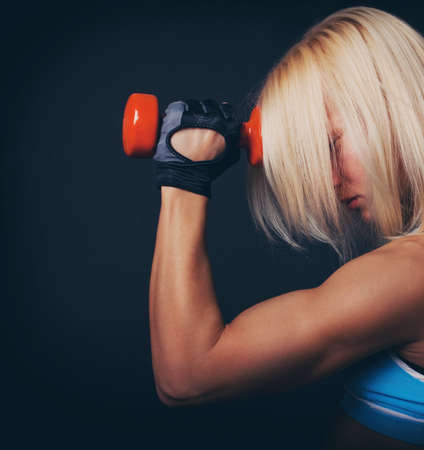 Good-shaped athletic girl stands and holds dumbbellの写真素材