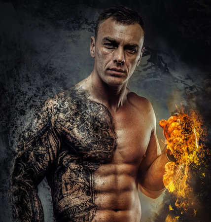 Portrait of awesome male model with naked muscular body. Isolated on dark grey background.の写真素材