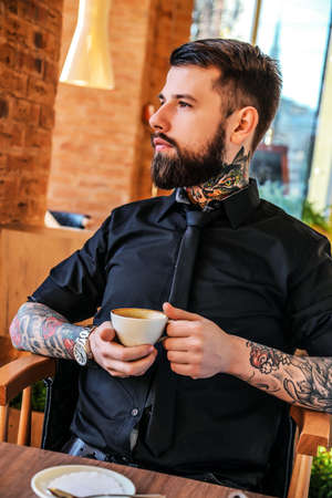 Guy with tattoos sitting at the table in a cafe.の写真素材