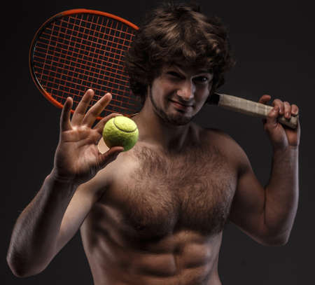 Male tennis player poses in studio. Isolated on grey.の写真素材
