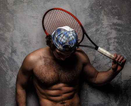 Male in white shorts with tennis racket over grey wall.の写真素材
