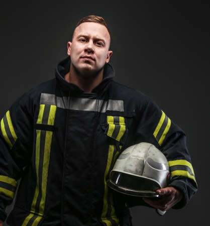 Firefighter in uniform posing in studio. Isolated on greyの写真素材