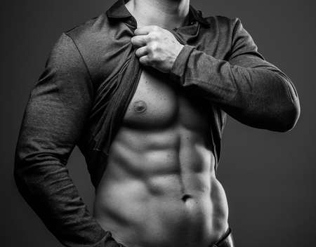 Muscular guy poses showing his abs and muscular bodyの写真素材
