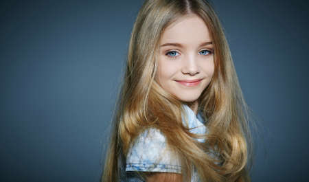 Cute long haired little girl posing in studio. Isolated on greuの写真素材