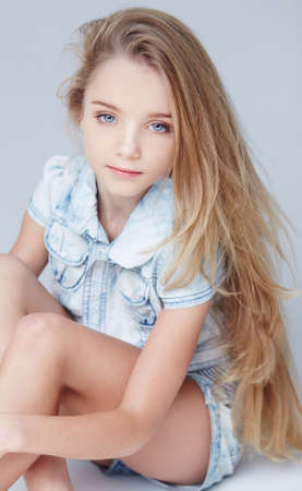 Cute long haired little girl posing in studio. Isolated on greuの写真素材