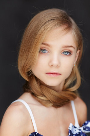 Portrait of young girl with blue eyes on dark background