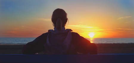 Girl sitting on a beach and looking on sinsetの写真素材