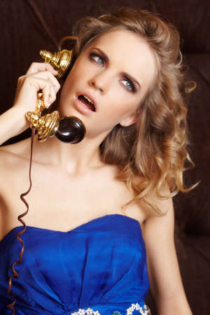 Blond female in blue dress speaking on phoneの写真素材