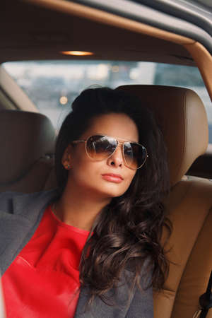 Brunette in grey jacket and red shirt in the car on back seats