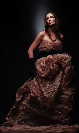 Art portrait of fashion middle age woman in long brown dress on dark backgroundの写真素材