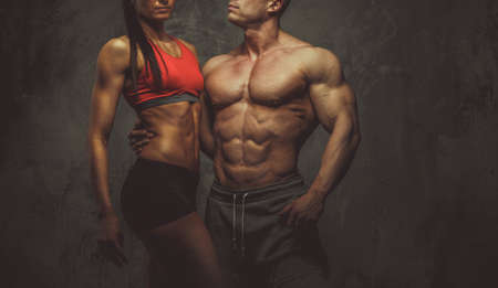 Man and woman bodybuilders couple posing on grey backgroundの写真素材