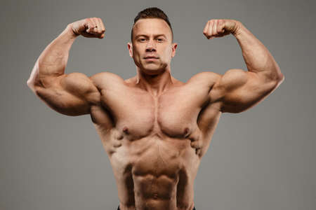 Awesome bodybuilder posing in studio on grey background.の写真素材