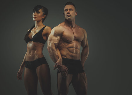Man and woman bodybuilders couple posing on grey backgroundの写真素材