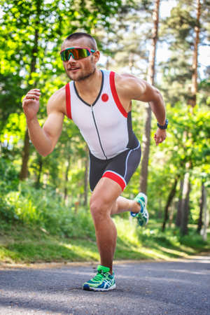 Male in sportswear and sunglasses running in the forest.の写真素材