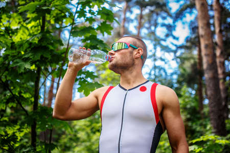 Man drinking water in the summer forest.の写真素材