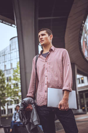 Guy on the modern street in casual clothing with laptopの写真素材