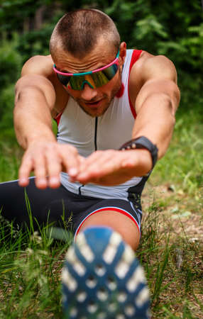 Male in sportswear doing body extension in the forest.