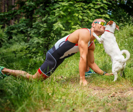 Fitness man in sportswear with his dog in the forest.の写真素材