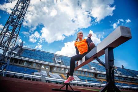 Female in sportswear doing exercises on the stadium.