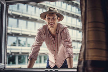 Smiling guy in big hat looking through window.の写真素材