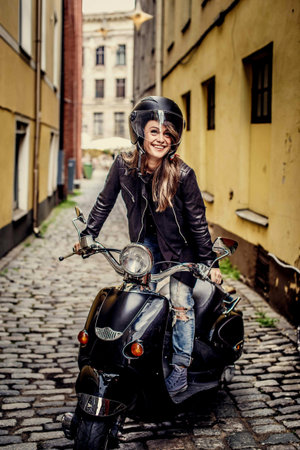 Casual girl sitting on scooter between two houses.