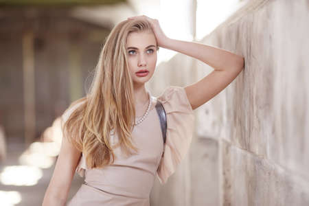 Sexy blond female in cream dress posing in a big hall.の写真素材