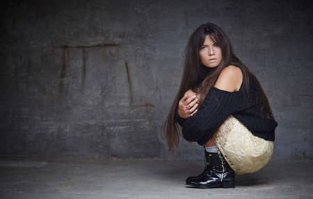 Beautiful woman with long brown hair in white shorts and black jacket posing on the floor in studio.の写真素材