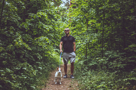 Attractive man in the forest with small dog on a walk.の写真素材