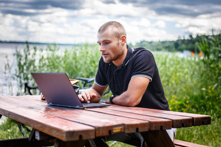 Man sitting at the table and wotking with laptop on nature.の写真素材