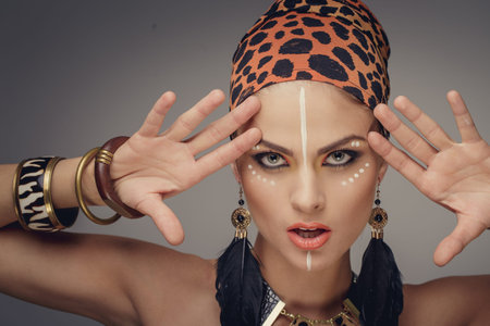 Young woman with exotic make up holdin hands near her face. Isolated on grey background.の写真素材