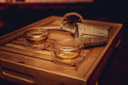 Glass tea cups in a shadow on wood tray.の写真素材