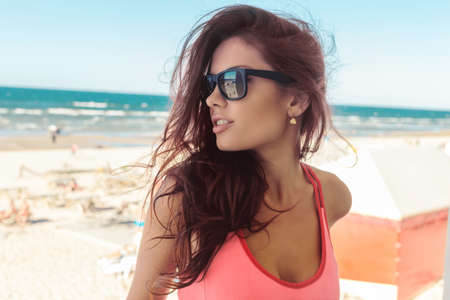 Close up portrait of sexy brunette girl in sunglasses over sea shore.の写真素材