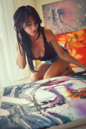 Awesome sexy female with dark long hair sitting on the floor and drawing big and colorfull picture.の写真素材