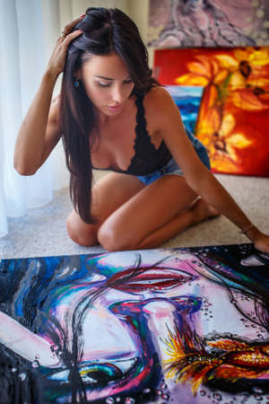 Awesome sexy female with dark long hair sitting on the floor and drawing big and colorfull picture.の写真素材