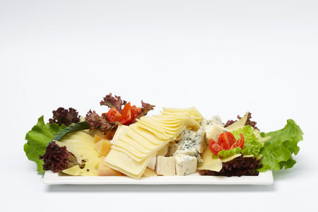 Some vegetables and pieces of cheese on white plate isolated on white background.の写真素材