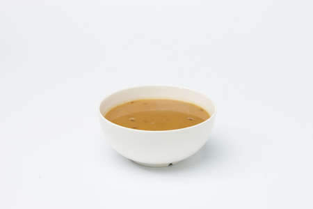 Yellow cream soup in white cup isolated on white background.の写真素材