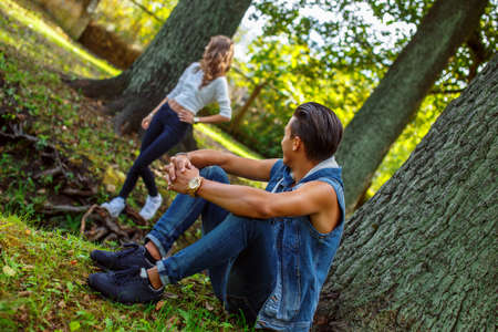Man sitting under tree and looking at his girlfriend.の写真素材