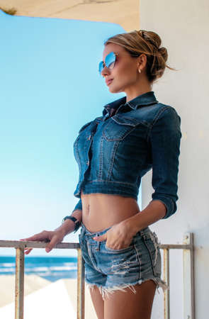 blond woman in jeans shorts and t-shirt posing over seaside.の写真素材