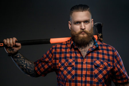 Serious man in red t shirt holding big axe. Isolated on grey background.の写真素材