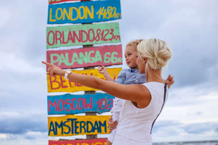 Blond woman with child over signpost destinations.