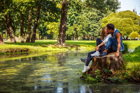 Male and female relaxing and kissing near river in a park.の写真素材